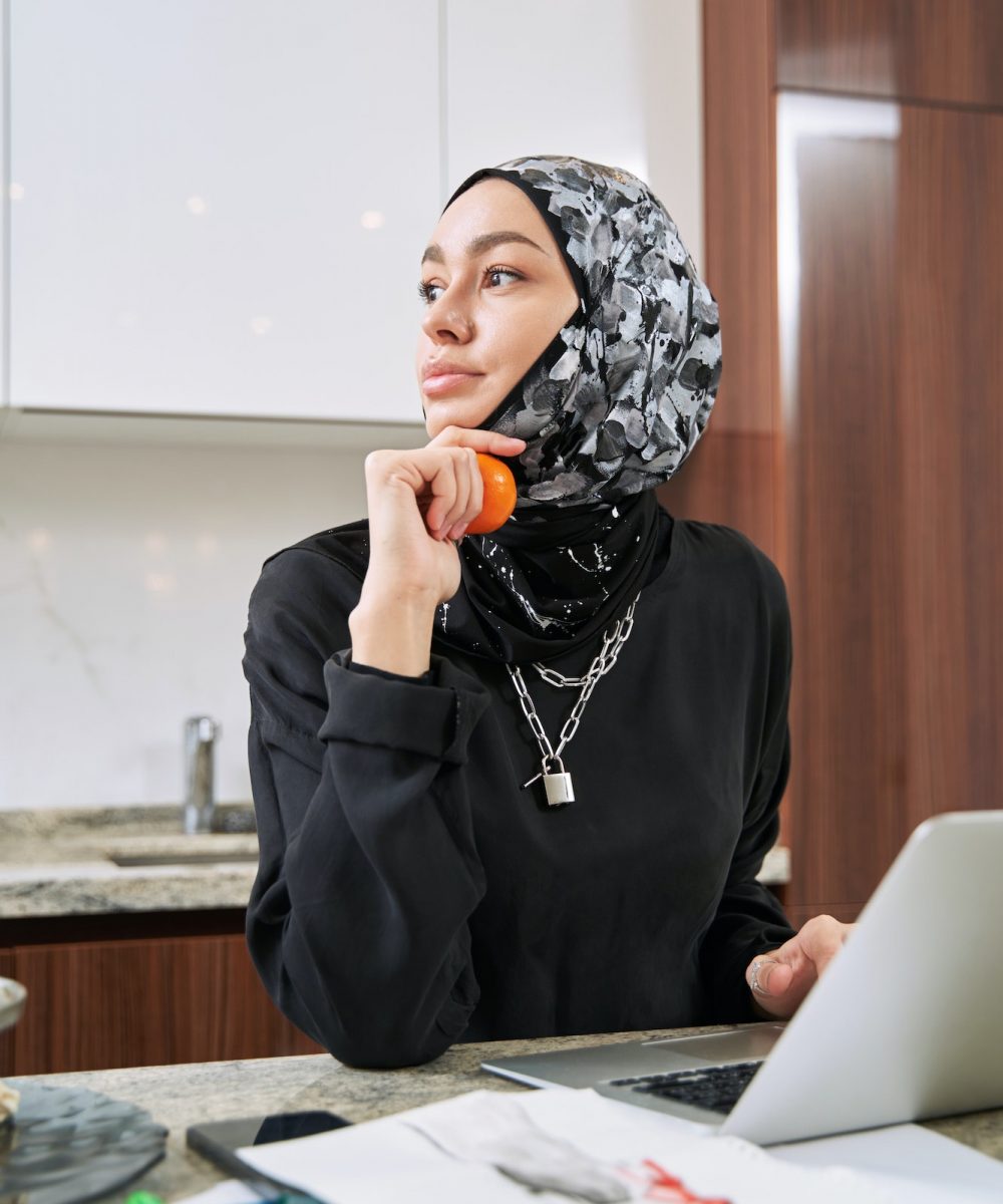 Happy muslim woman studying with laptop at home
